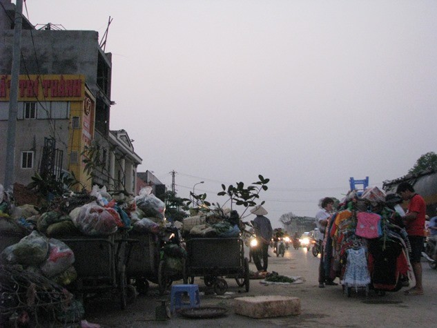 Người dân Hà Nội phớt lờ trước những đống rác đang vây quanh mình để buôn bán.