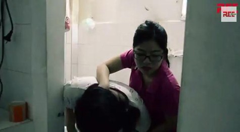 Tái hiện cảnh bảo mẫu ghì đầu trẻ vào bồn cầu nhà vệ sinh để ép ăn. Ảnh cắt từ clip.