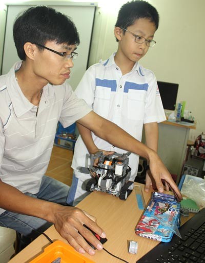 Thầy Cường chỉ dẫn học sinh cài đặt phần mềm để robot hoạt động.