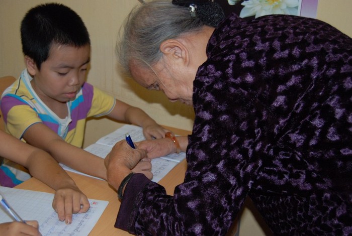 Bà giáo Nam đang dạy các cháu tập viết. (Ảnh: Đỗ Quyên)