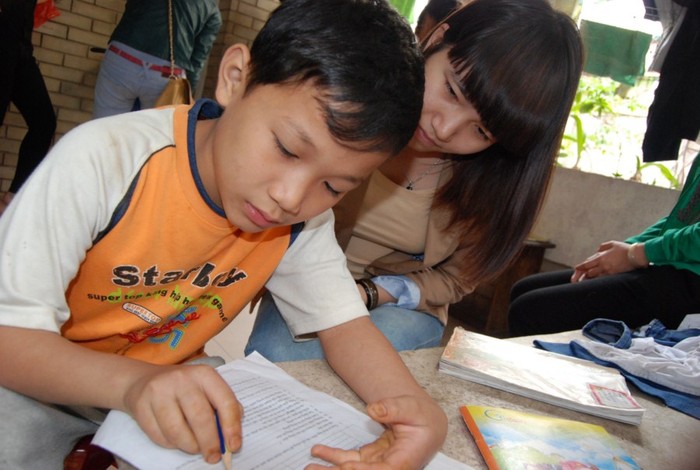 Gia sư hướng dẫn trẻ em trong làng trẻ SOS học bài.