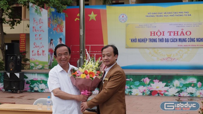 Đại diện trường Trung học phổ thông Tử Đà, thầy giáo Bùi Tuấn Long tặng hoa Nhà giáo nhân dân Nguyễn Lân Dũng. (Ảnh: LC)