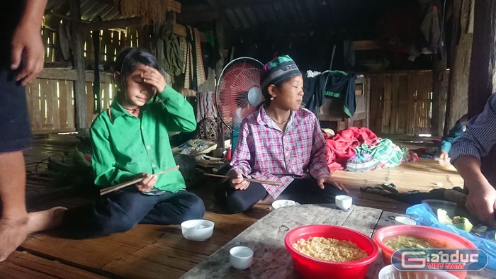 Ly Thị Óng (áo xanh) và bữa cơm với mỳ tôm của những đứa trẻ người La Chí. (Ảnh Nguyễn Toan)