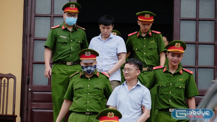 Đỗ Mạnh Tuấn và Nguyễn Quang Vinh (đeo kính) dẫn giải ra khỏi phòng xử án. Ảnh TP