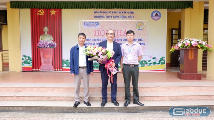 Thầy giáo Nguyễn Văn Mơ và Thầy giáo Nguyễn Đình Linh tặng hoa và chụp ảnh lưu niệm cùng Tiến sĩ Trần Công Trục. Ảnh: LC