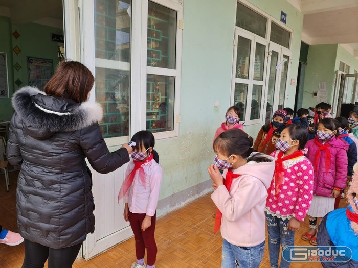 Đo nhiệt độ cho học sinh tại trường Phổ thông bán trú Tiểu học Đồng Văn B. Nhiều em học sinh còn bỡ ngỡ nhưng thực hiện tốt việc đo nhiệt độ trước khi vào lớp.