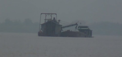 Ngay tại bến phà Đông Ninh hàng chục tàu lớn đang gầm rú hút cát dưới dòng sông. Ảnh cắt từ clip