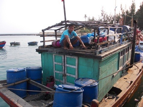 Ngư dân Bùi Văn Phải đang thu xếp những vật dụng còn lại trên cabin chiếc thuyền của mình bị Trung Quốc bắn cháy.