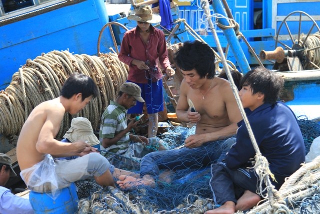 Nhiều ngư dân trên tàu QNg 98402TS đến từ Quảng Ngãi ai nấy tay thoăn thoắt vá lại mảnh lưới bị rách sau chuyến đi biển lần trước để chuẩn bị ra khơi.