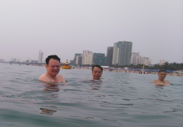 Ông Nguyễn Điểu (bên trái), giám đốc Sở Tài nguyên và Môi trường TP Đà Nẵng xuống biển tắm vào sáng ngày 30/4. Ảnh: H.L