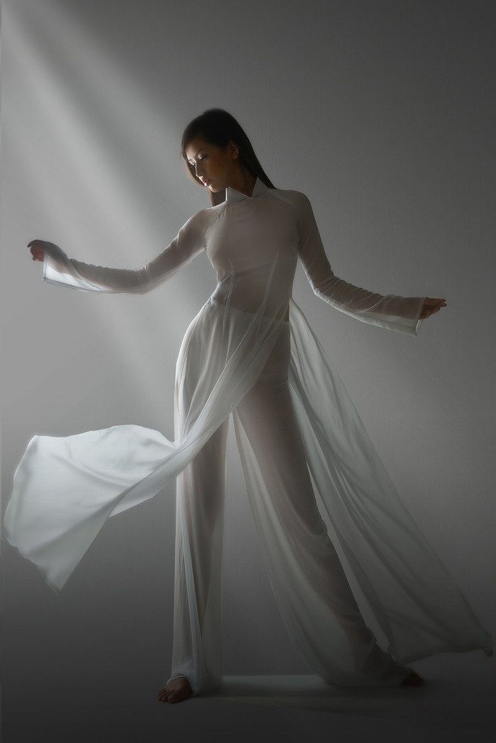 Tà áo dài trắng tinh khiết, tung bay trong gió, đôi chân trần của cựu hoa hậu càng làm cho hình ảnh thêm ấn tượng.