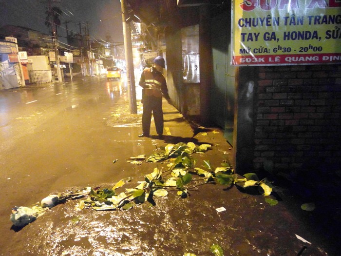 Công nhân vệ sinh Trần Hoàng Vinh đang quét dọn lá cây rụng trên đường Lê Quang Định. Anh cho biết, cơn mưa giông trong ngày hôm nay làm cho anh rất vất vả.