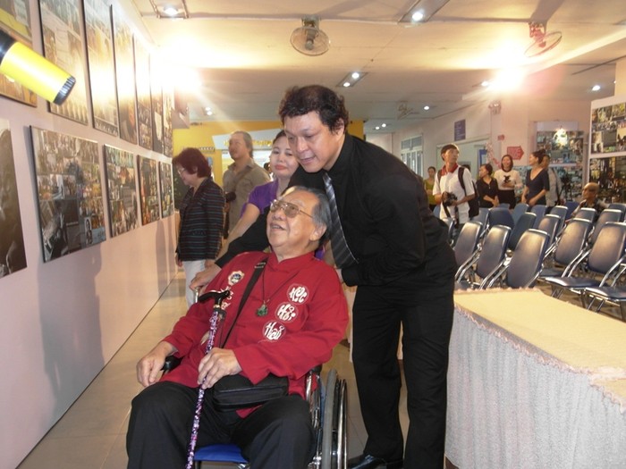 Tuổi già, sức yếu, phải ngồi xe lăn, GS.TS Trần Văn Khê được nhiếp ảnh gia Nguyễn Á đẩy xe đi xem ảnh.