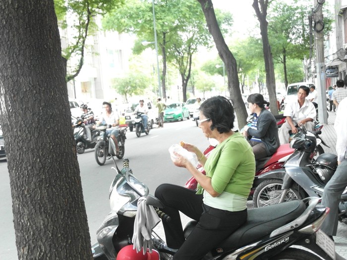 Một phụ huynh lót dạ bằng bánh mì trước cổng trường Trần Đại Nghĩa.