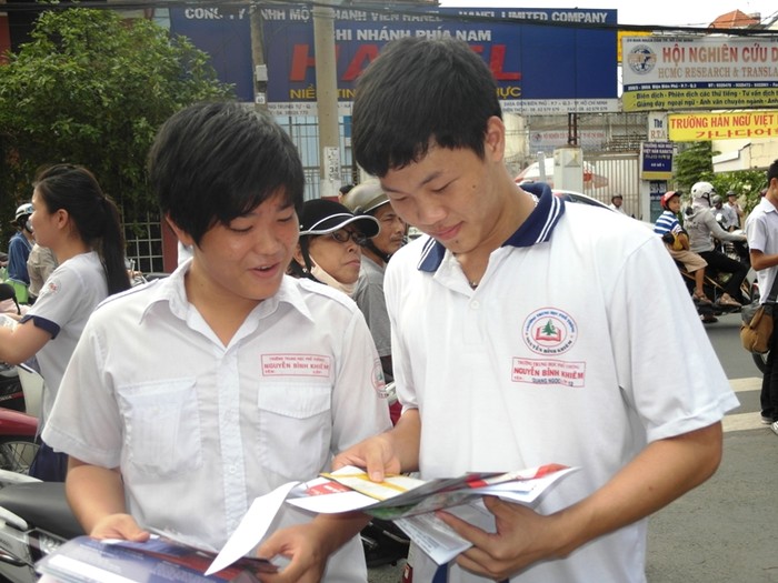 Hai nam sinh trường Nguyễn Bỉnh Khiêm vô tư xem quảng cáo các trường Đại học, Cao đẳng trên tờ rơi. Câu học sinh Quang Ngọc (phải) cho biết: “Đề thi tiếng Anh tương đối dễ. Em yên tâm đậu tốt nghiệp rồi”.