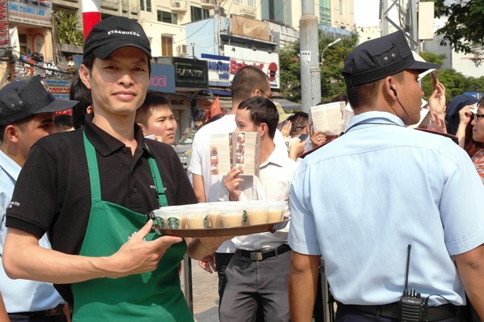 Một nhân viên Starbucks bưng những cốc cà phê sữa bé tí ra "miễn phí" cho các "thượng đế".