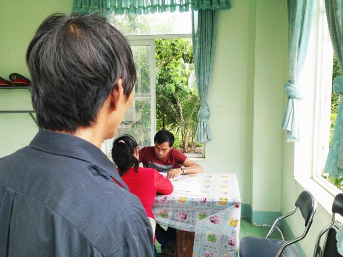 Ông Lê Đình Phú đang nhìn vợ mình làm việc với công an điều tra. Ảnh: Dương Cầm