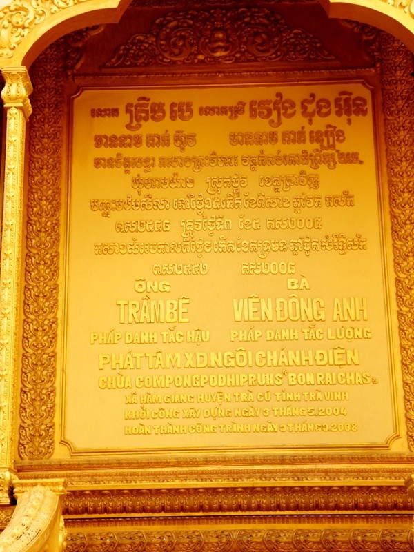 Bảng công đức ghi tên ông Trầm Bê và vợ, bà Đông Anh trên vách cổng chính vào chánh điện chùa Vàm Ray.