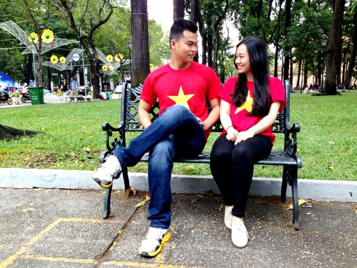 Một đôi bạn trẻ mặc áo hình cờ Tổ quốc đang ngồi trò chuyện tại công viên Thống Nhất.
