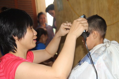Chị Đoàn Thị Thu Huyền đang cắt tóc cho các em học sinh ở Ngòi Hoa