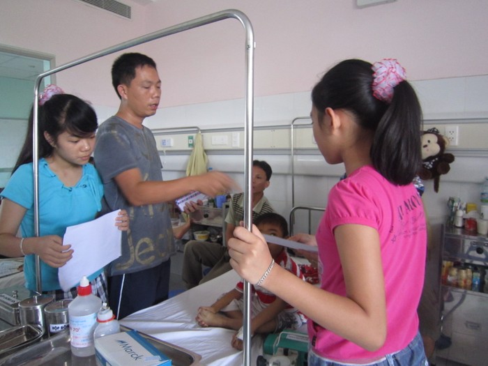Ba bố con anh Nguyễn Ngọc Khoa trao tiền ủng hộ các trường hợp khó khăn của lớp học Hy vọng đang phải nằm điều trị trên giường bệnh