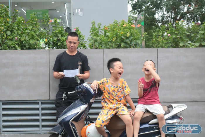Anh Tuyến cùng 2 con trai đứng chờ thí sinh tại điểm thi trường Trung học cơ sở Thanh Xuân, Hà Nội. Ảnh: Doãn Nhàn