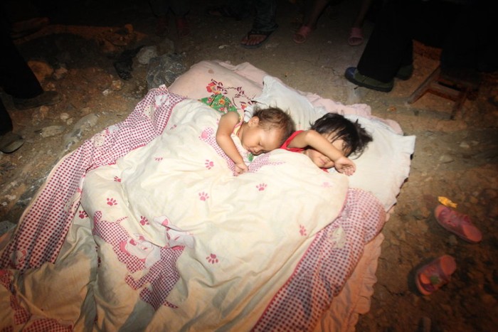Hai chị em được bố mẹ lấy chăn đệm cho ngủ tạm ngoài nền đất