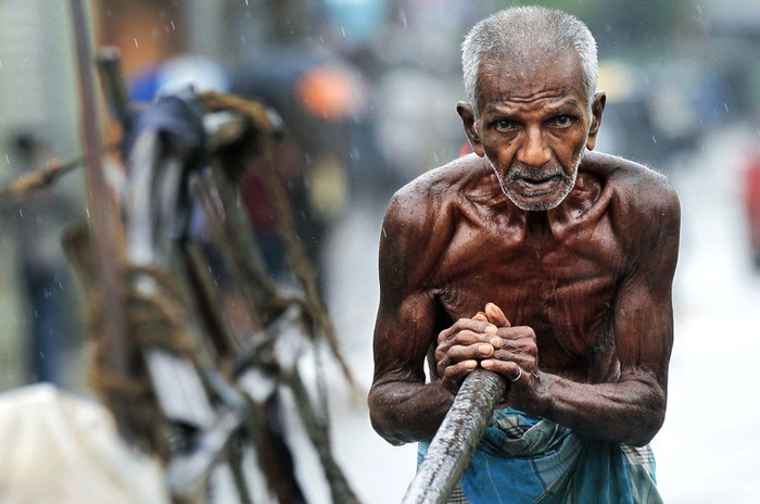 Một người phu đẩy xe hàng trong mưa tại Sri Lanka hôm 4/9