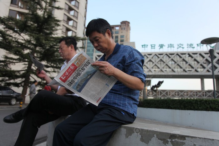 Hai người dân Bắc Kinh chăm chú đọc, tờ Thời báo Hoàn Cầu giật tít: Nhật Bản kinh hoàng trước 6 tàu Hải giám Trung Quốc đổ bộ lên đảo (Điếu Ngư/Senkaku)