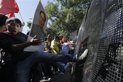 Ôm ảnh Mao Trạch Đông làm bình phong, chân đạp hàng rào an ninh trước cổng Đại sứ quán Nhật Bản do cảnh sát thiết lập