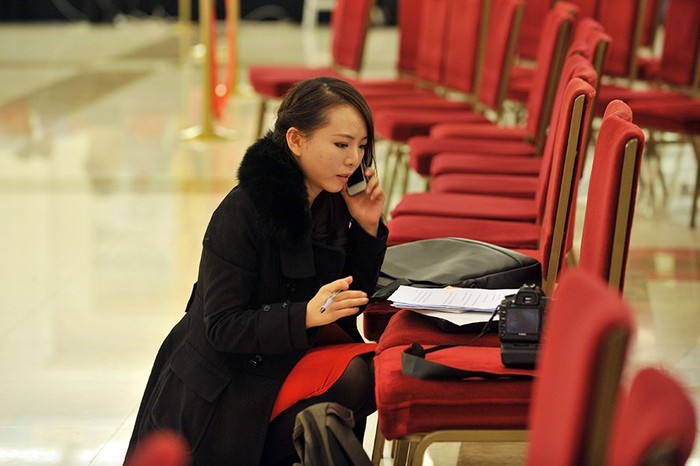 Một nữ phóng viên tranh thủ tác nghiệp bên ngoài hành lang phòng họp báo