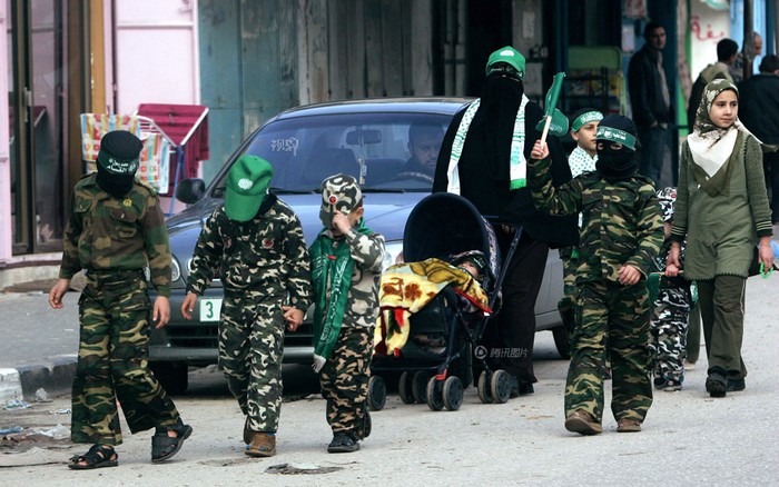 Một người phụ nữ dẫn những đứa trẻ mặc quân phục tham gia hoạt động do Hamas khống chế