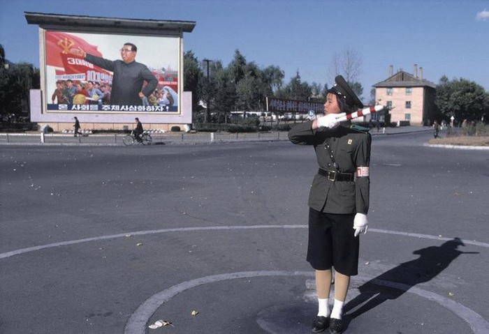 Nữ giao thông viên trước ngã 3 có bức phù điêu lãnh tụ Kim Nhật Thành