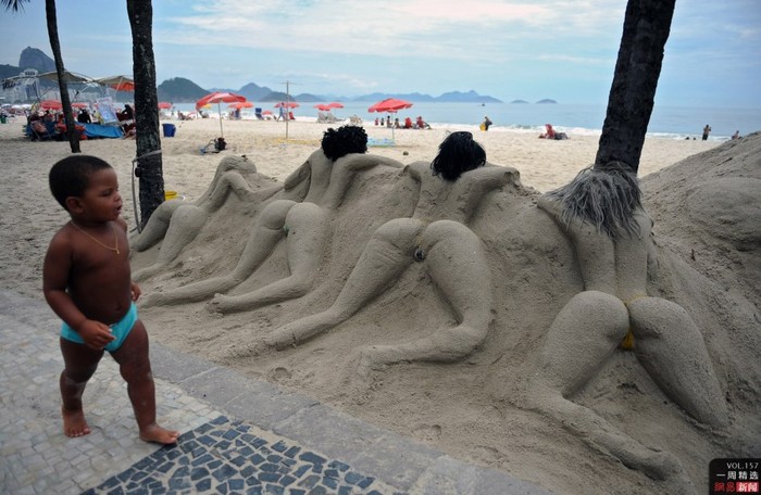 Một cậu bé ở Rio de Janeiro, Brazil đi qua tác phẩm tạo hình bằng cát trên bãi biển