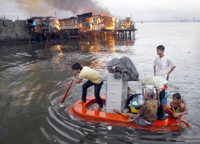 Cư dân chèo thuyền tạm chạy hỏa hoạn khi ngọn lửa thiêu rụi ngôi nhà tại một khu ổ chuột ở Manila, Philippines, ngày 11 tháng 5. Ít nhất 1.000 ngôi nhà đã bị phá hủy trong vụ hỏa hoạn.