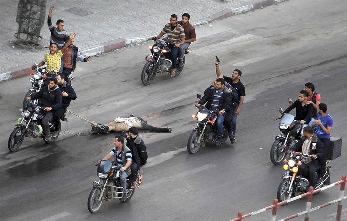 Những tay súng Palestine kéo cơ thể của một người đàn ông bị nghi ngờ làm việc cho Israel chạy khắp thành phố trên Dải Gaza vào ngày 20/11