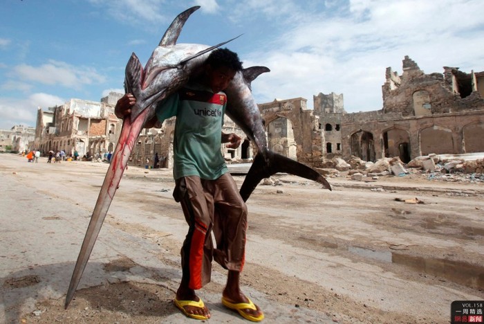 Ngày 18 tháng 12, tại Mogadishu, Somalia, một thanh niên vác con cá kiếm vừa bắt ra chợbans