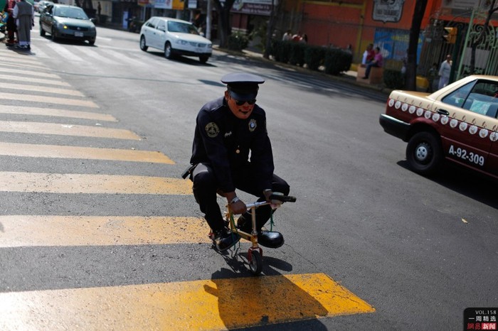 Một chú hề trong trang phục cảnh sát giao thông cưỡi xe đạp mi ni trên đường phố thủ đô Mexico hôm 18/12
