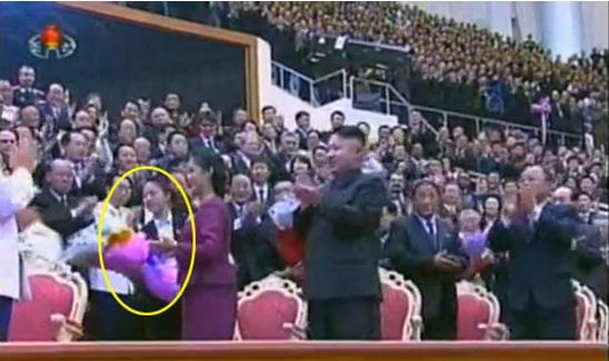 Đệ nhất phu nhân Ri Sol-ju trao bó hoa cho nữ nhân viên an ninh đứng sau mình