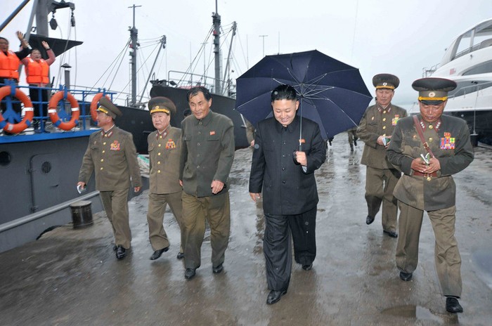 Ông Kim Jong-un cầm ô rời khỏi cầu cảng nơi neo đậu của các tàu cá quân sự Bắc Triều Tiên với khuôn mặt vui vẻ