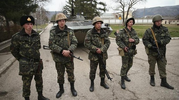 Lính và xe tăng Ukraine đứng bên trong cổng 1 căn cứ quân sự tại Crimea trong vòng vây của những người có vũ trang được cho là quân đội Nga hoặc tự vệ thân Nga.