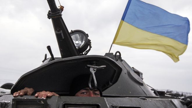 Một người lính Ukraine hé nắp tháp xe tăng nhìn ra ngoài quan sát khu vực giáp ranh giữa Kherson với Crimea.