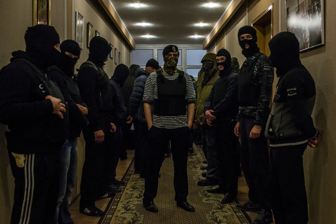 Những người đàn ông đeo mặt nạ canh gác bên trong tòa thị chính Donetsk mà người biểu tình vừa chiếm đóng.