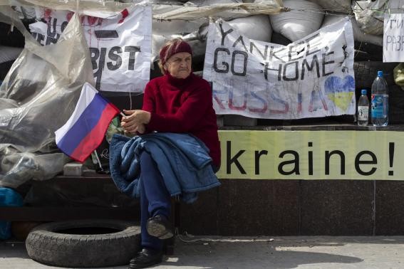 Một phụ nữ Donetsk cầm cờ Nga ngồi trước hàng rào trụ sở chính quyền đang do lực lượng ly khai kiểm soát.