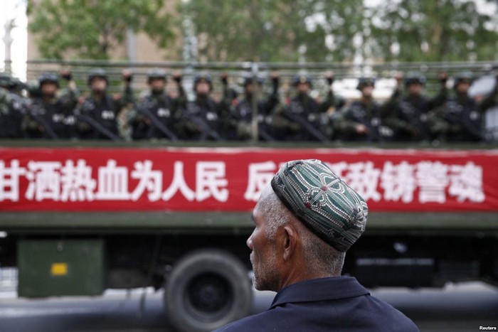 Một người đàn ông Duy Ngô Nhĩ quan sát lính Trung Quốc đổ về Urumqi thủ phủ Tân Cương, ảnh: VOA.