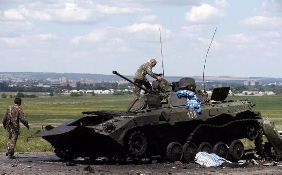 Lính Ukraine đang kiểm tra một chiếc xe bọc thép đã bị phá hủy tại Slaviansk hôm 5/7.