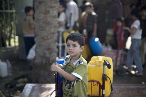 Một đứa trẻ Palestine đang chờ đợi để lấy nước uống trong khoảng thời gian ngừng bắn hiếm hoi.