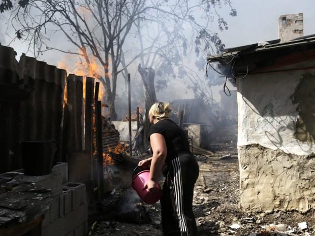 Đọ súng, đọ pháo vẫn xảy ra tại miền Đông Ukraine bất chấp lệnh ngừng bắn đã được ký kết, người dân Ukraine dập lửa sau khi ngôi nhà của họ bị trúng đạn pháo.