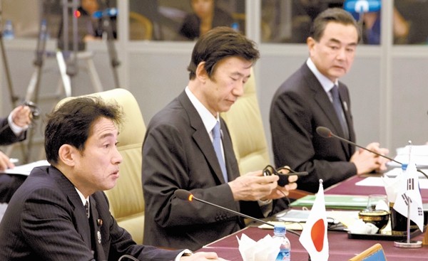 Ngoại trưởng Trung Quốc Vương Nghị (phải) liếc nhìn người đồng cấp Nhật Bản Fumio Kishida (trái) trong cuộc họp 3 bên Nhật - Hàn - Trung.