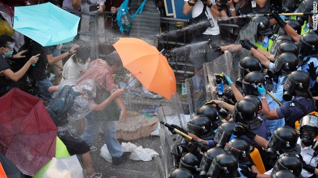 Người biểu tình dùng ô, dù, áo mưa để chống đỡ.